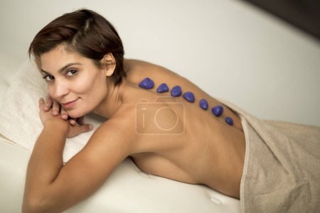 Photo for Woman with bob hair relaxes on the bed of a spa lying on her stomach shot from above with her back in the foreground - Royalty Free Image
