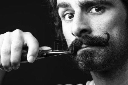 Photo for Man fixes his mustache with pliers - Royalty Free Image