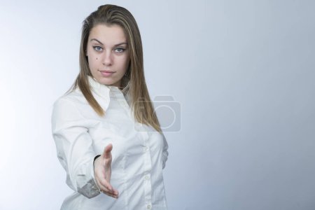 Foto de Chica rubia en camisa blanca hace la señal de estrechar las manos, aislado sobre fondo claro - Imagen libre de derechos