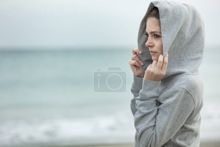 Foto de Mujer con capucha posando frente al océano - Imagen libre de derechos