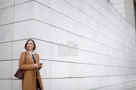 Téléchargez les photos : Blonde femme manager avec cheveux frisés, chemise blanche, cravate noire et manteau beige - en image libre de droit