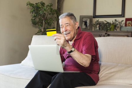 Téléchargez les photos : Homme d'âge moyen assis à la maison en utilisant un ordinateur portable - en image libre de droit