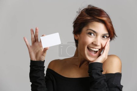 Foto de Morena chica con el pelo bob muestra una tarjeta blanca con una hermosa sonrisa, aislado en el fondo uniforme - Imagen libre de derechos