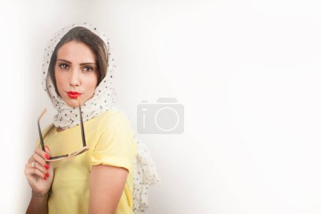 Foto de Chica rubia con la cabeza bufanda y camisa amarilla vestido estilo de los años 50 está aislado sobre fondo gris - Imagen libre de derechos