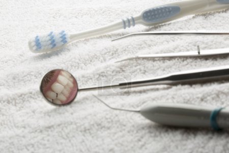 Foto de Detalles de un cepillo de dientes y el espejo de un dentista que refleja una sonrisa, aislados sobre una toalla - Imagen libre de derechos