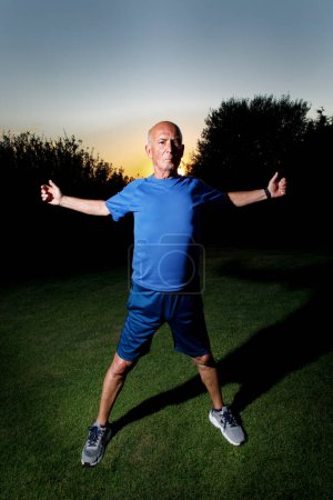 Photo for Mature man doing exercise outdoors in the evening at the park. concept of healthy life. - Royalty Free Image