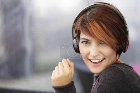 Téléchargez les photos : Belle fille brune écoutant de la musique avec des écouteurs sur les oreilles - en image libre de droit