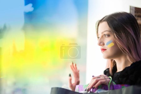 Foto de Retrato de cerca de la mujer con manchas de pintura de bandera ucraniana en la cara - Imagen libre de derechos