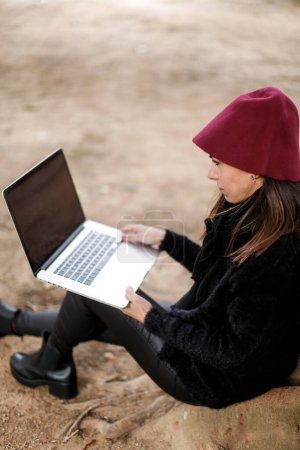 Téléchargez les photos : Brunette fille habillée en noir avec ordinateur portable - en image libre de droit