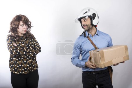 Foto de Mensajero con casco hace la entrega de un paquete a una dama disgustada, aislado sobre fondo blanco - Imagen libre de derechos