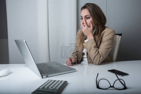 Foto de Gerente mujer en chaqueta es incrédulo y molesto sentado delante de su ordenador portátil - Imagen libre de derechos