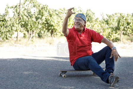 Photo for Senior in red jersey enjoys skateboarding on a country road - Royalty Free Image
