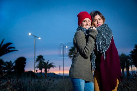 Téléchargez les photos : Portrait de couple de belles femmes en vêtements chauds dans la rue pendant le crépuscule - en image libre de droit
