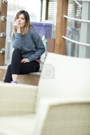 Téléchargez les photos : Portrait de belle fille brune regardant avec une expression sérieuse assis dans un cadre extérieur - en image libre de droit