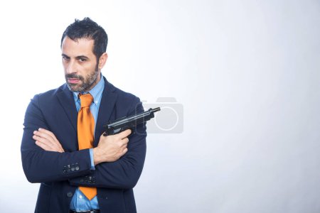 Téléchargez les photos : Homme brun avec barbe vêtu d'une veste orange et cravate pointe un pistolet blanc - en image libre de droit