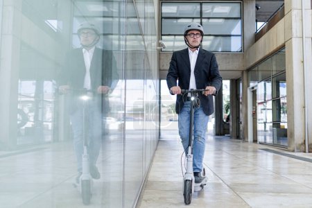 Foto de Hombre de negocios senior montando scooter eléctrico - Imagen libre de derechos