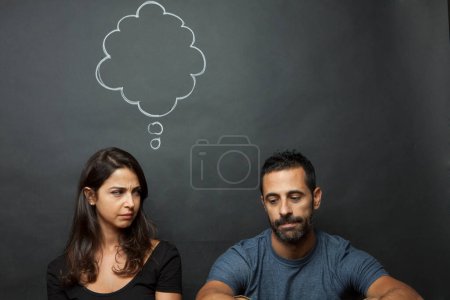 Photo for Engaged couple and perplexed while at the top appears an empty cloud drawn in the background with the girl's thoughts. - Royalty Free Image