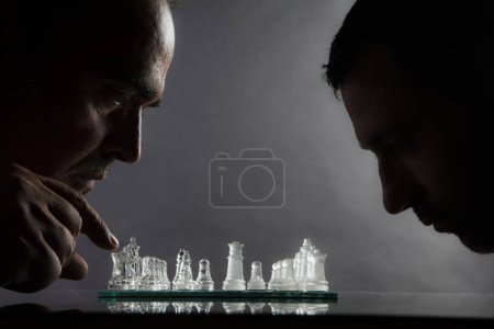Foto de 2 ajedrecistas juegan ajedrez, desafían, uno frente al otro, aislados sobre fondo gris - Imagen libre de derechos