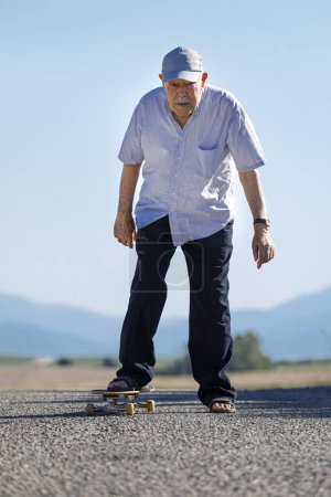 Foto de Ochenta años disfruta del skateboarding en una carretera rural - Imagen libre de derechos