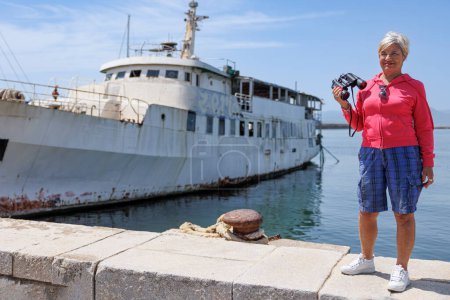 Foto de Retrato de una mujer mayor con un binocular delante del barco - Imagen libre de derechos