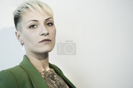 Téléchargez les photos : Blonde tatouée femme manager, vêtue d'une veste verte isolée sur fond blanc - en image libre de droit