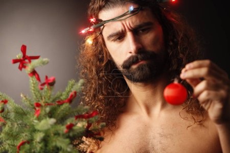 Photo for Young handsome bearded man with christmas tree on blurred background - Royalty Free Image