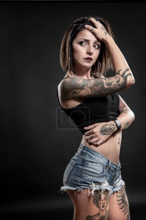 portrait of beautiful young woman with tattoos on grey background