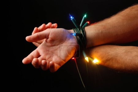 Photo for Hands tied by wire of the Christmas lights - Royalty Free Image