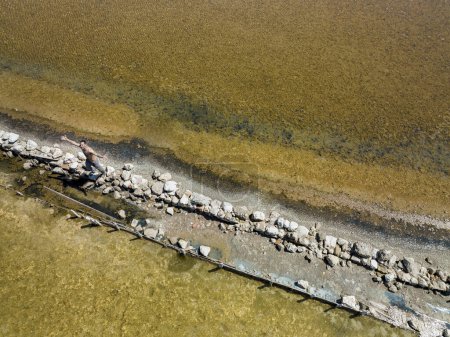 Téléchargez les photos : Image panoramique d'un étang prise par un drone, au milieu passe une route étroite qui sépare les eaux. - en image libre de droit