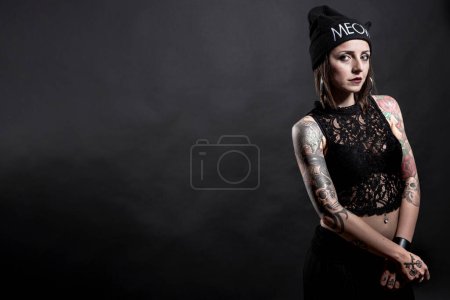 portrait of beautiful young woman with tattoos on grey background