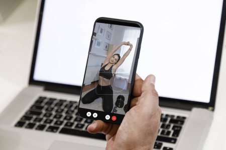 Foto de Detalles de la mano de un hombre sosteniendo su teléfono móvil conectar en la que la pantalla muestra a una chica haciendo ejercicios - Imagen libre de derechos