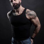 Portrait of handsome bearded man with tattoos on dark background