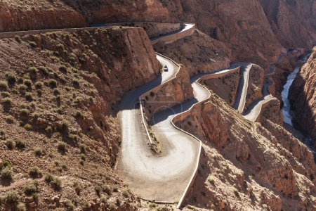 Foto de Curving serpentine winding road in Dades Gorge mountain canyon. Famous touristic landmark of Morocco, R704 Way. Aerial view. - Imagen libre de derechos