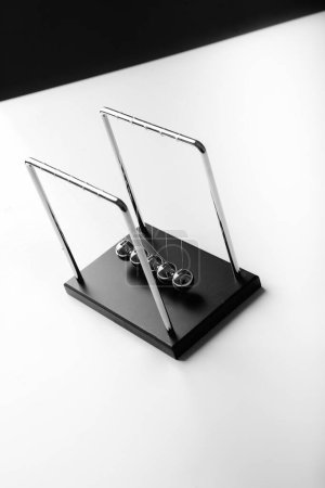 Photo for Newton cradle pendulums steel kinetic balls hand pulling one - Royalty Free Image