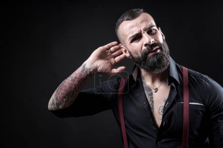 Téléchargez les photos : Portrait d'un bel homme barbu fort avec des tatouages sur fond sombre - en image libre de droit