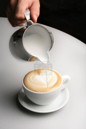 Photo for A cup of coffee with a heart shape shaped foam in a white plate on a white background - Royalty Free Image
