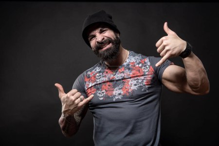 Photo for Portrait of handsome angry bearded man with tattoos on dark background - Royalty Free Image