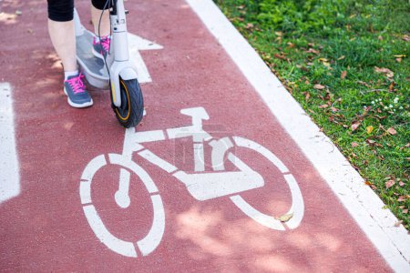 Photo for Details of a cycle path with white markings on the ground and the injured part of an electric scooter - Royalty Free Image