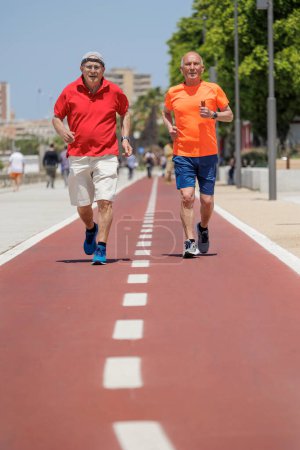 Téléchargez les photos : Hommes âgés en tenue de sport exercice sur une piste rouge - en image libre de droit