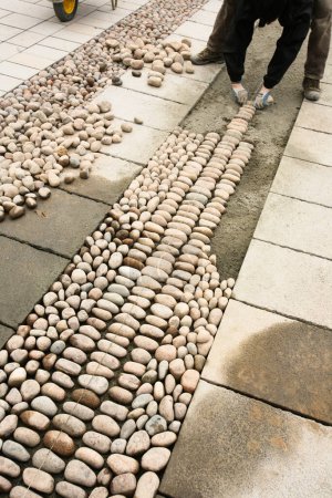 Téléchargez les photos : Gros plan de professionnel faisant trottoir de galets sur la rue de la ville - en image libre de droit