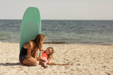Foto de Madre en un traje de baño junto con su hija divertirse en una playa junto al mar. - Imagen libre de derechos