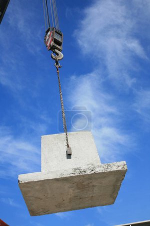 Photo for Crane lifting cement mixer container against blue sky. - Royalty Free Image