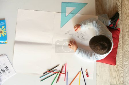 Téléchargez les photos : Ittle garçon peinture à la table avec des fournitures d'art, vue de dessus - en image libre de droit