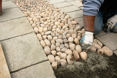 Photo for Close-up shot of professional making pebble walkway on city street - Royalty Free Image