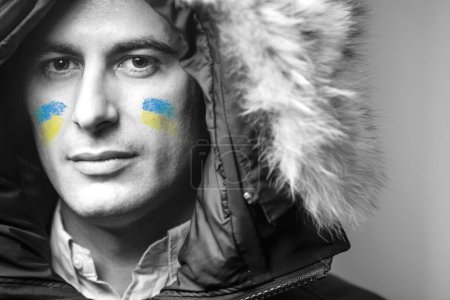 Foto de Retrato de cerca del joven guapo con manchas de pintura de bandera ucraniana en la cara, detener el concepto de guerra - Imagen libre de derechos