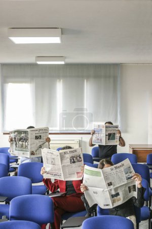 Foto de Gente leyendo el periódico mientras suttung en sillas - Imagen libre de derechos
