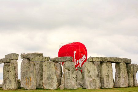 Foto de Un plano vertical de una antigua estatua de piedra roja en un parque - Imagen libre de derechos