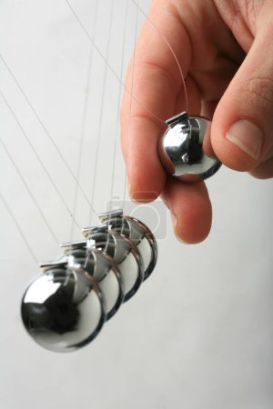 Foto de Newton péndulos cuna bolas cinéticas de acero mano tirando de uno - Imagen libre de derechos
