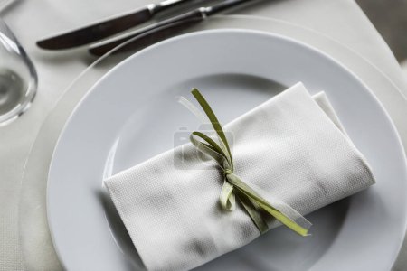 Téléchargez les photos : Détail d'une assiette avec un mouchoir enveloppé dans un ruban vert dessus - en image libre de droit