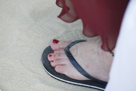 Téléchargez les photos : Vue rapprochée du pied féminin en flip-flop sur sable - en image libre de droit